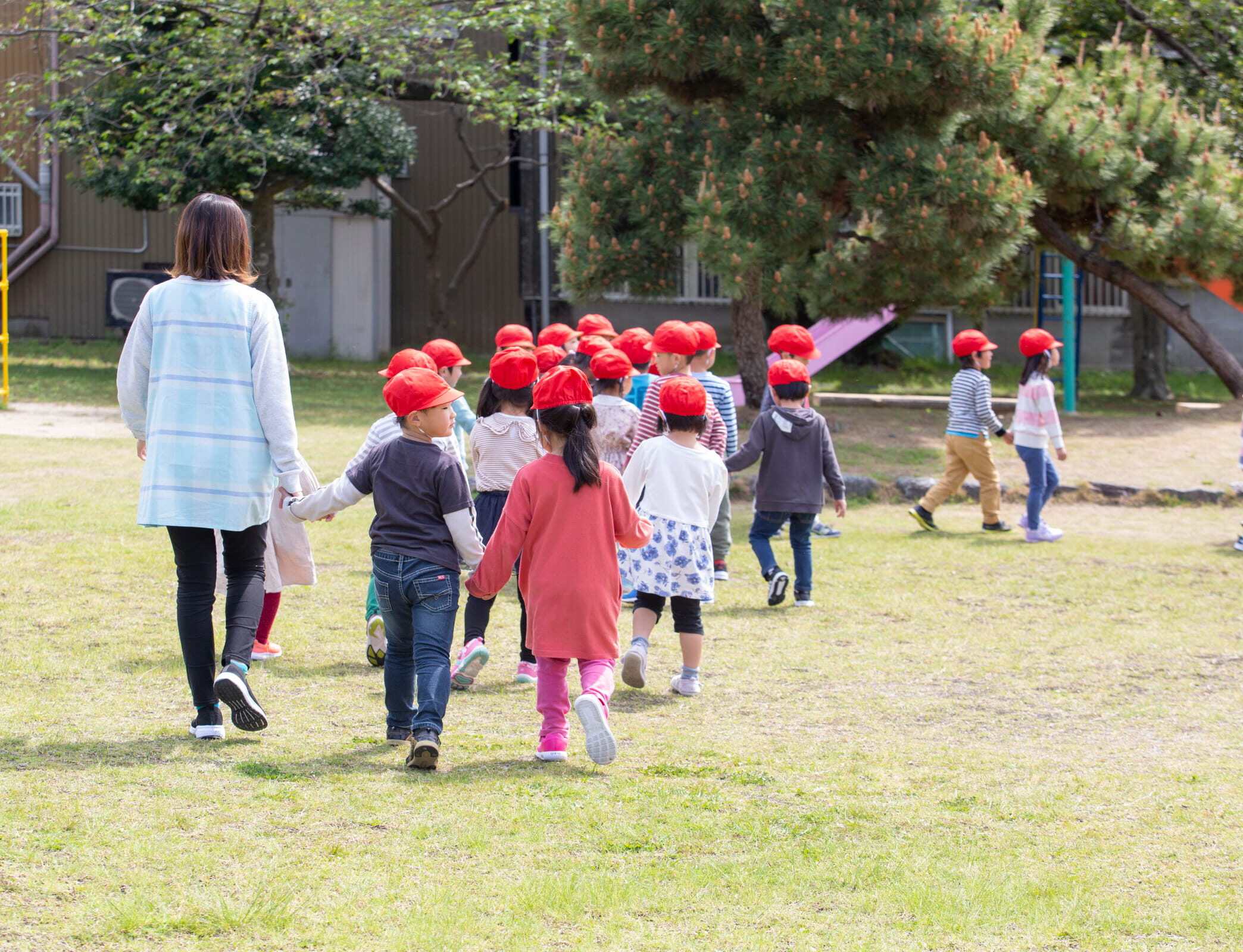 園庭を歩く子どもたちと職員